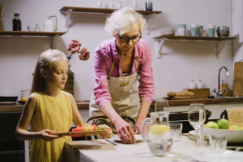 A resident and her granddaughter fixing a salad in the kitchen