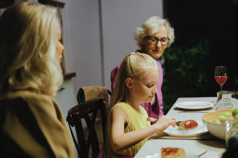 A resident at the holiday table with her granddaughter