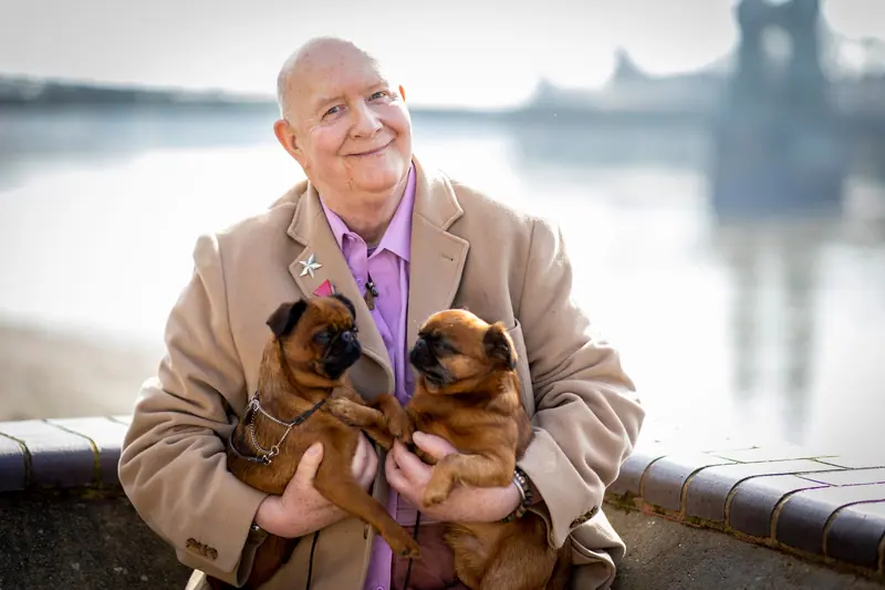 A resident holding two puppies against his tweed jacket