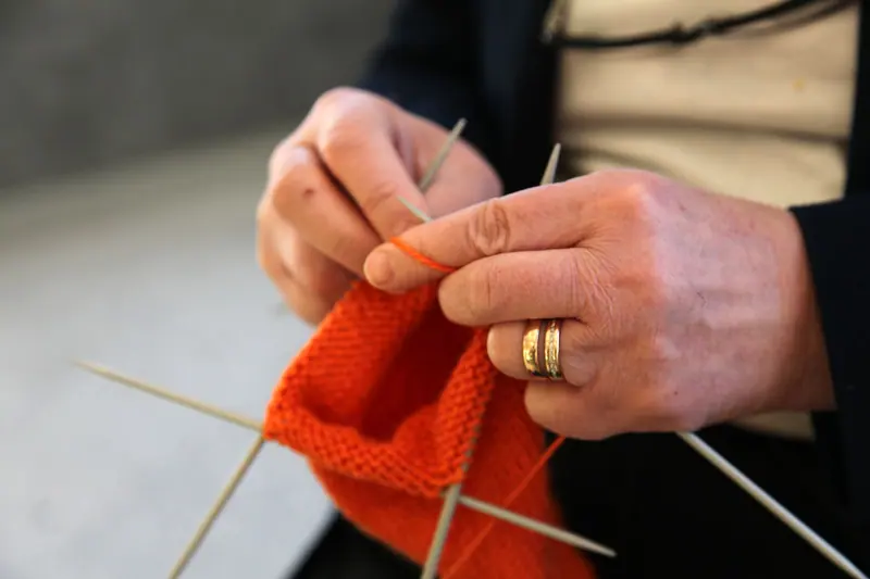A resident knitting a bright orange scarf