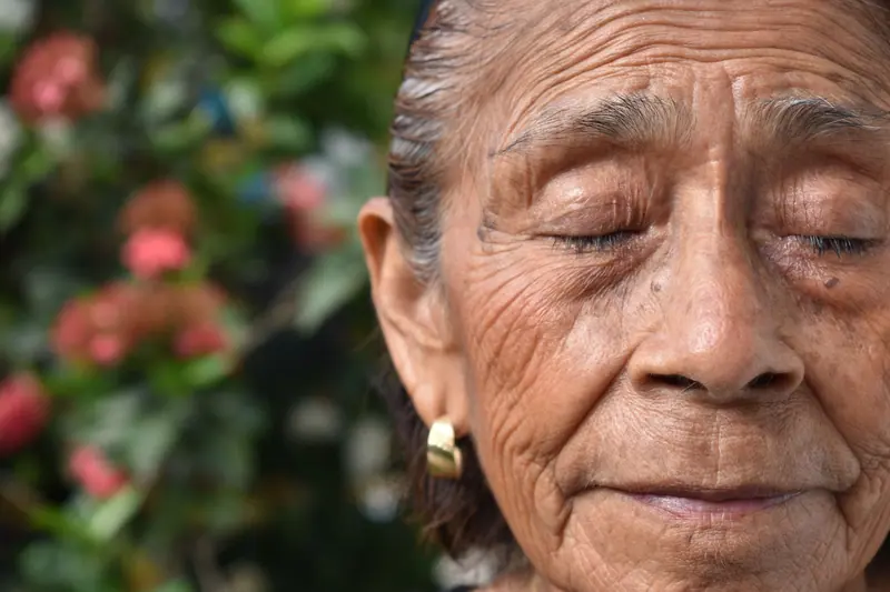 A resident with her eyes closed in the garden sun