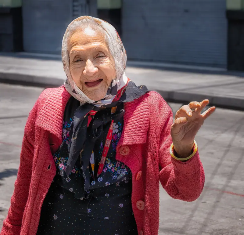 A resident in a red cardigan telling a story on the sidewalk