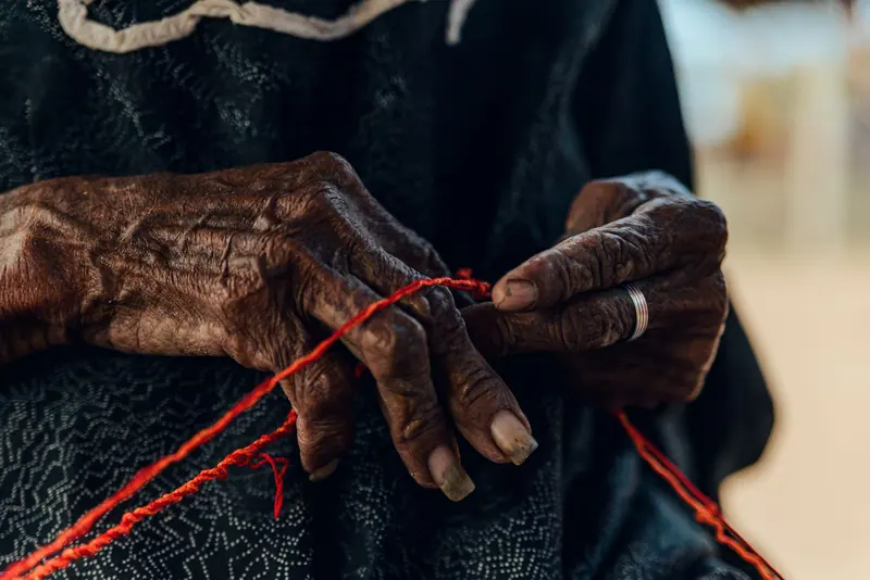 A resident's hands winding red yarn