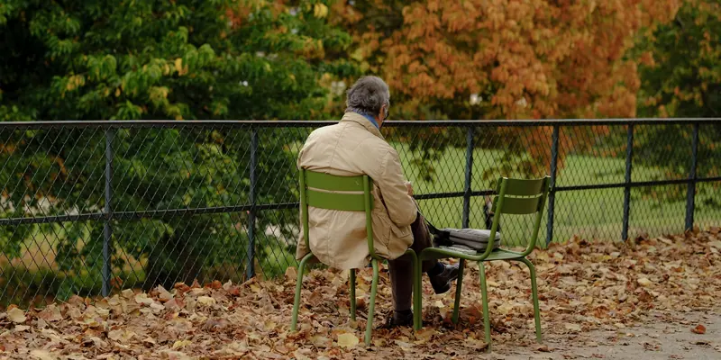 A resident on a bench among the fallen leaves