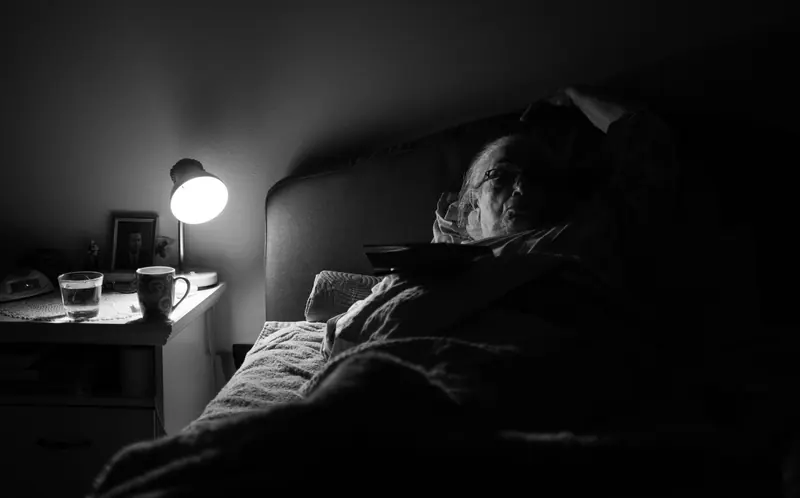 A bedside lamp glowing in a dark room at bedtime