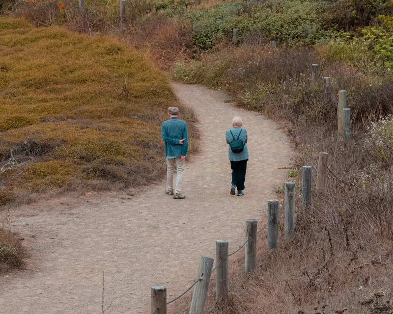 Two residents walking the fenced creek path in autumn