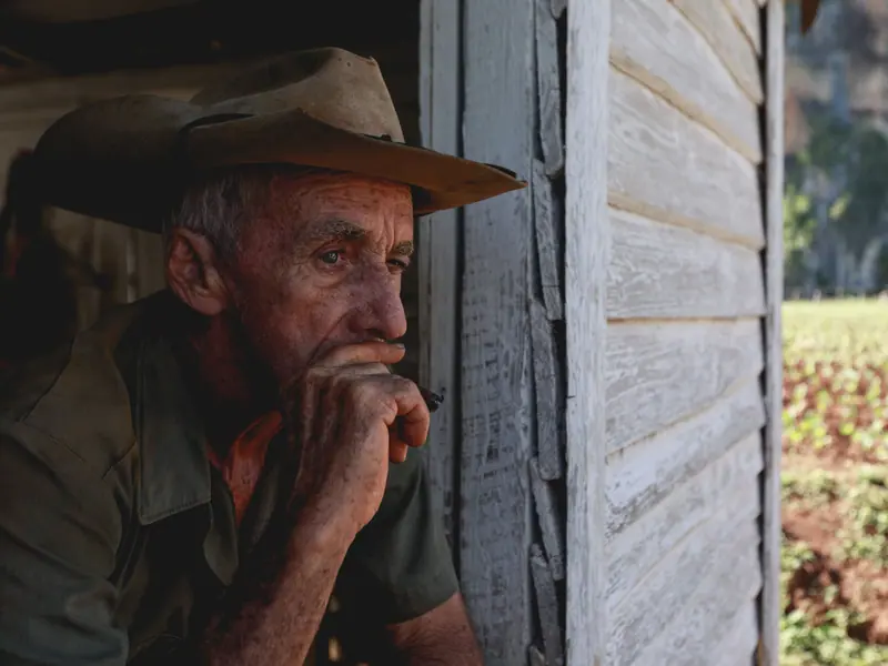 A farmer in a hat thinking in the barn doorway