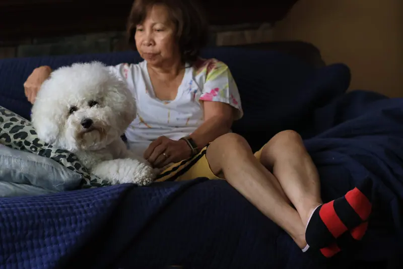 A resident on the couch with a white poodle beside her