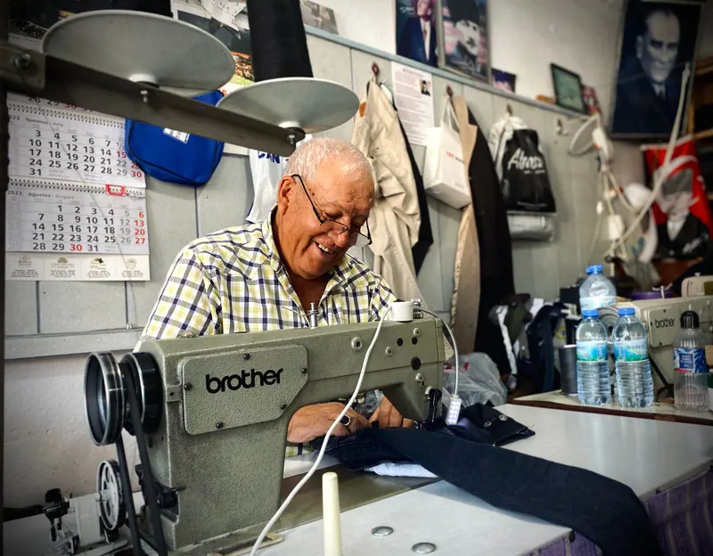 A resident at his sewing machine, mending a jacket