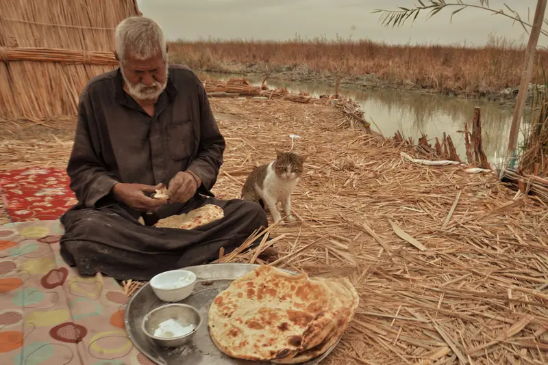 A farmer sharing his lunch on a blanket in the field