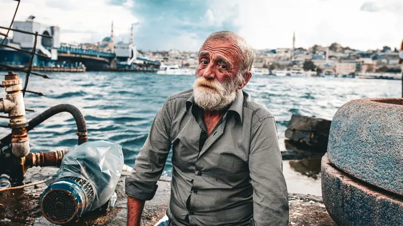 A resident with a white beard sitting by the harbor