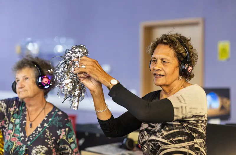Two residents in headphones laughing during afternoon music hour