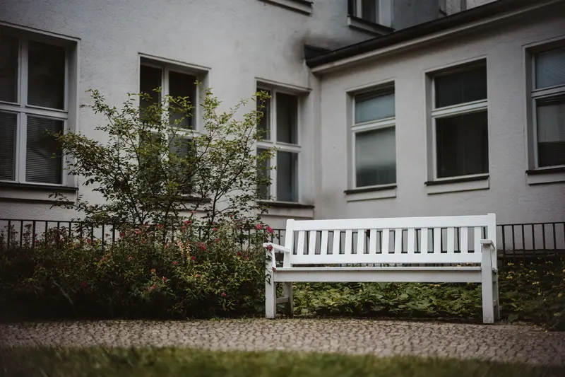 A white bench beside the cottage flower bed
