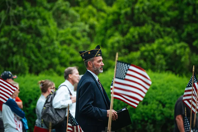A veteran in a garrison cap carrying a flag