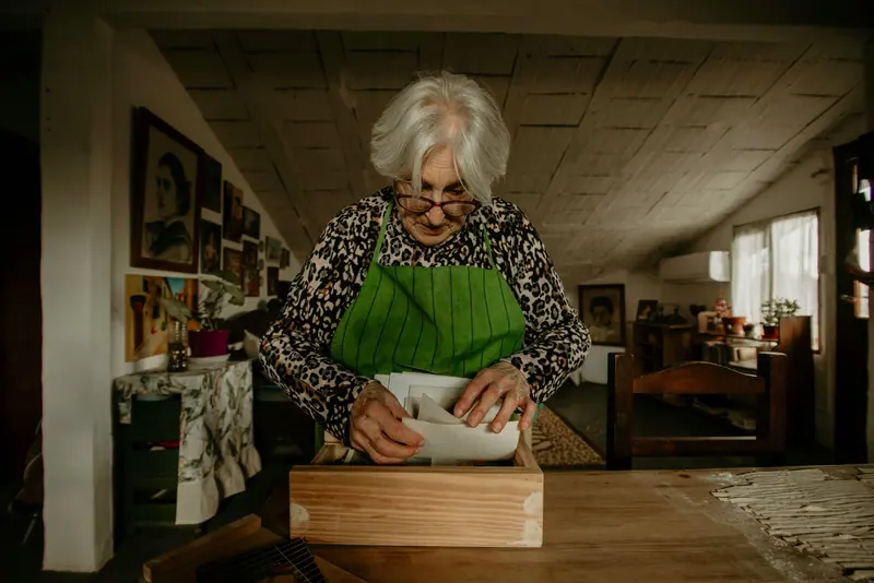 A resident in a green apron rolling dough at the kitchen counter