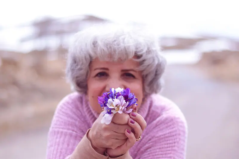 A resident in lilac holding a bunch of violets to paint