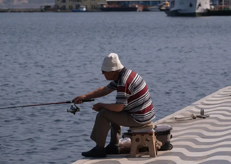 A resident fishing from his stool on the pier