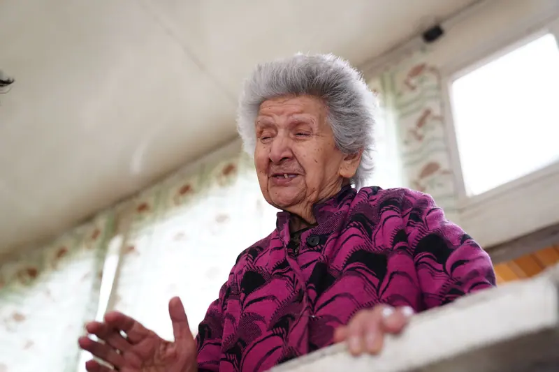 A resident in a purple sweater talking by the window