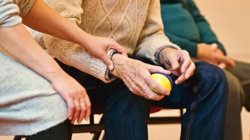 A caregiver holding a resident's hand on the sofa
