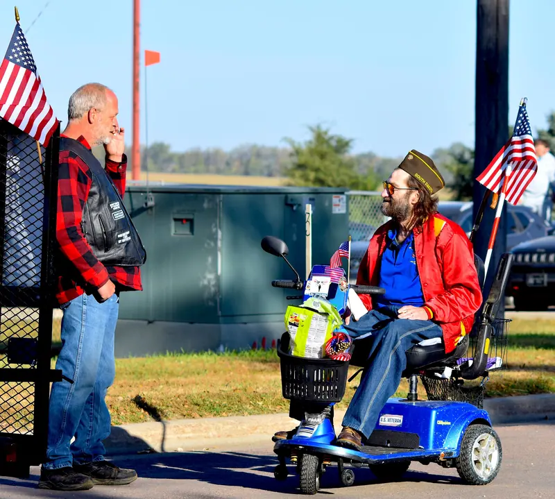 A veteran on his scooter at the parade, flags flying