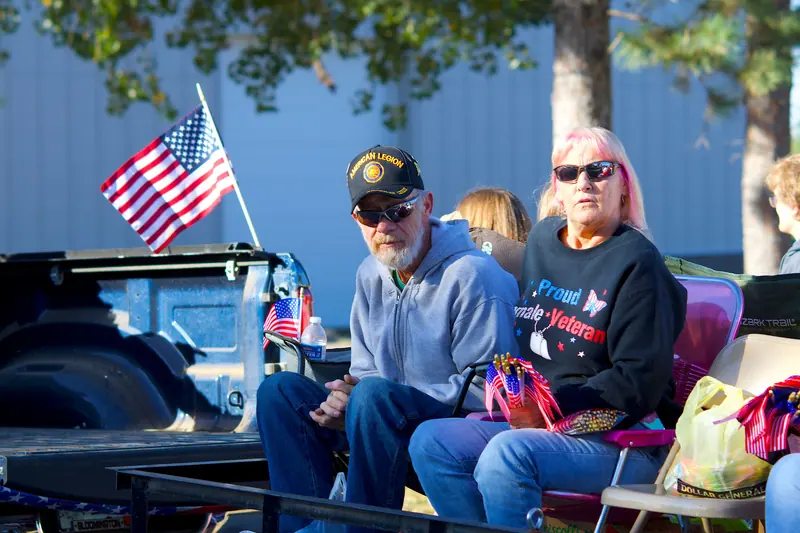 Residents in veterans' caps watching the Veterans Day parade