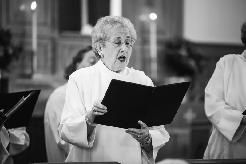 A resident singing from a hymnal, in black and white