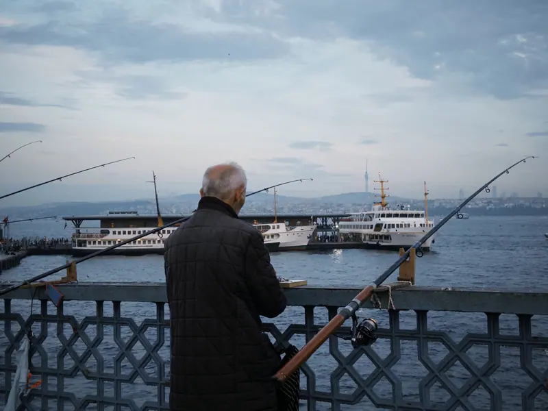 A resident with his rod at the rail, boats in the distance