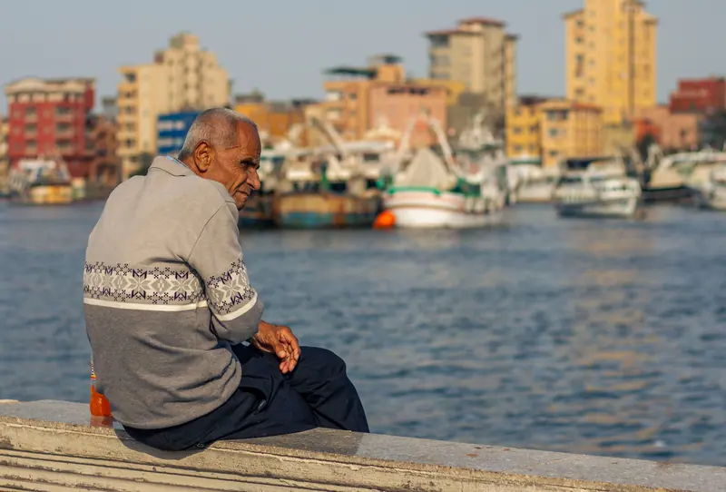 A resident in a sweater on the harbor wall