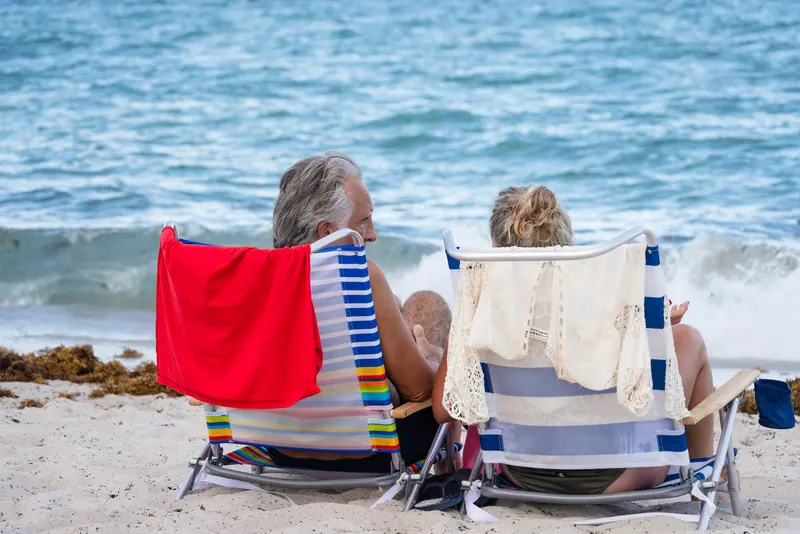 A couple in striped beach chairs facing the surf