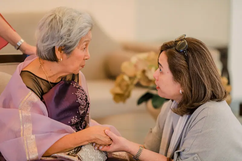 A caregiver holding a resident's hands as they talk in the sitting room