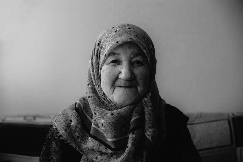 Black-and-white portrait of a resident in a headscarf, smiling