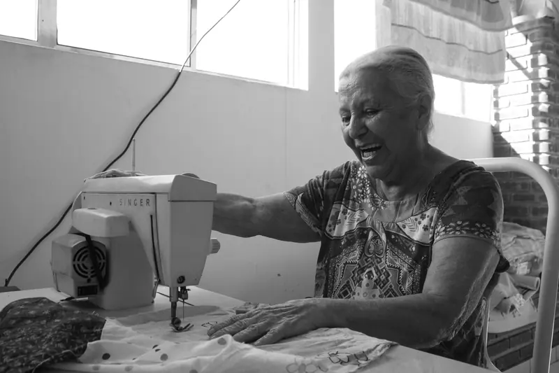 A resident laughing as she sews