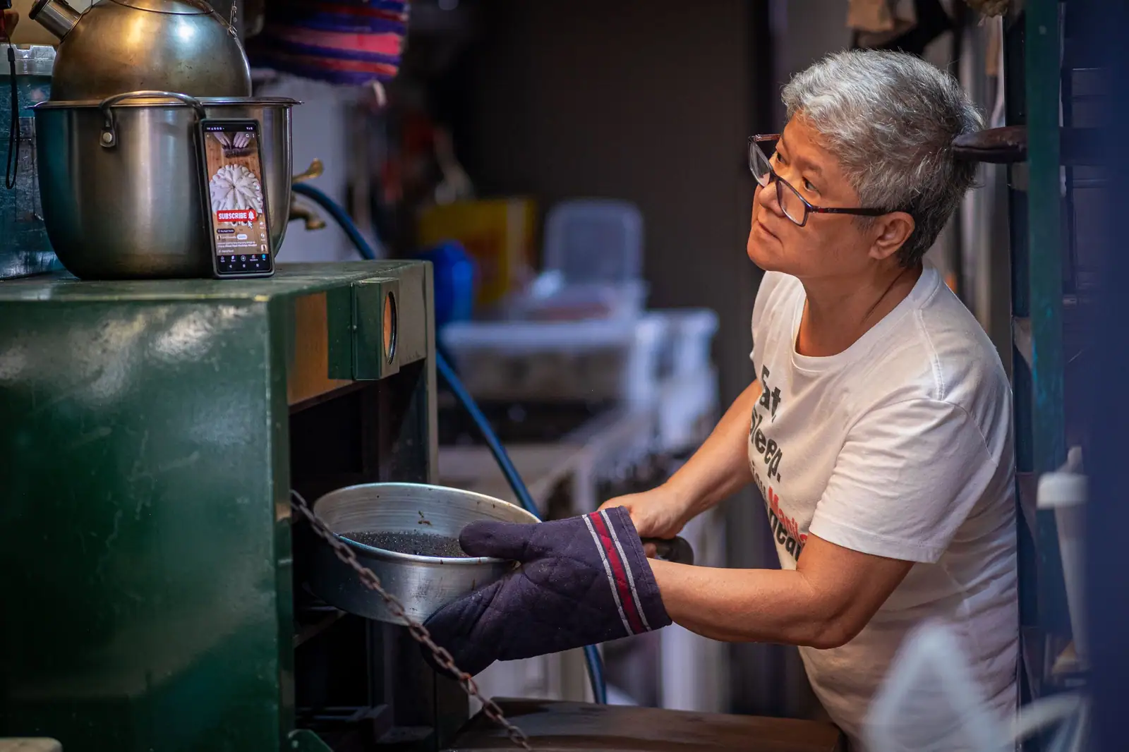 A resident in oven mitts lifting a pot from the stove during afternoon cooking