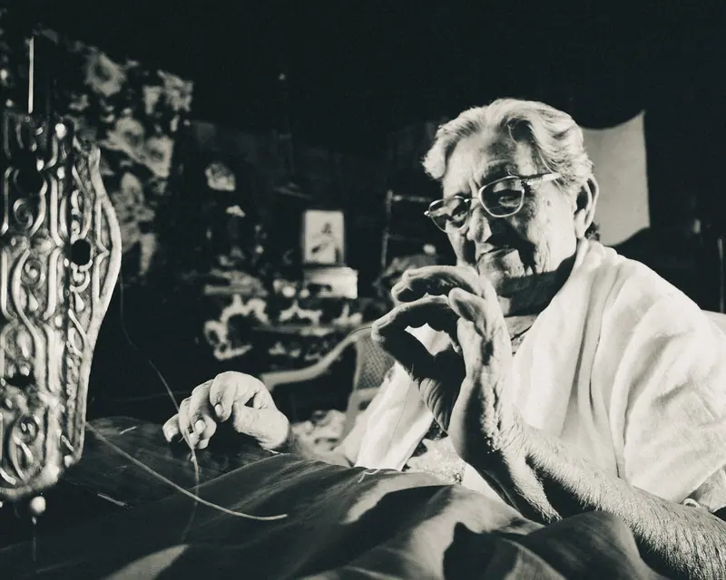 A resident smiling as she threads a needle