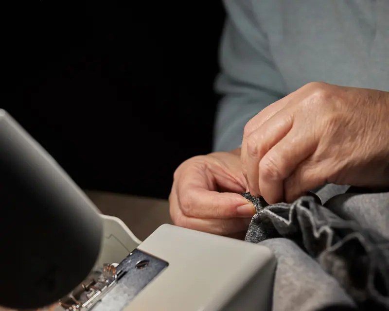 Hands guiding fabric under the sewing machine