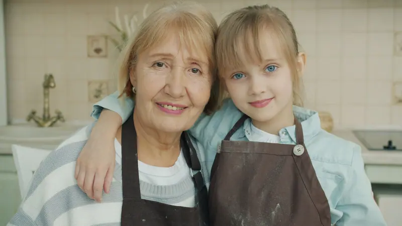 A resident and her granddaughter in matching aprons