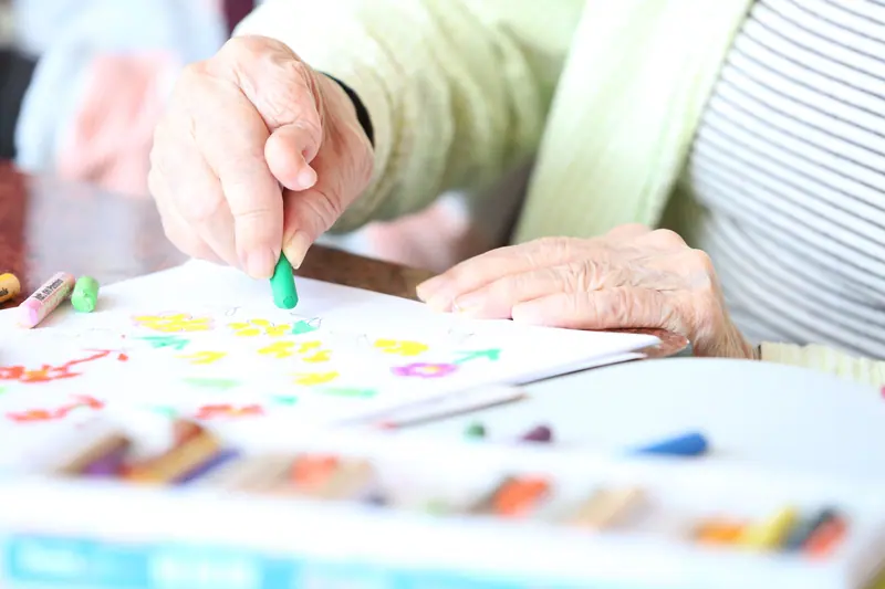 A resident adding dots of color with a crayon