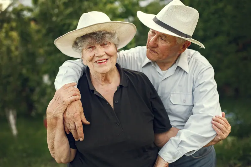 A couple posing arm in arm by the spring flower beds