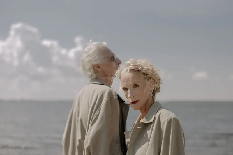 A husband and wife by the water in their spring coats