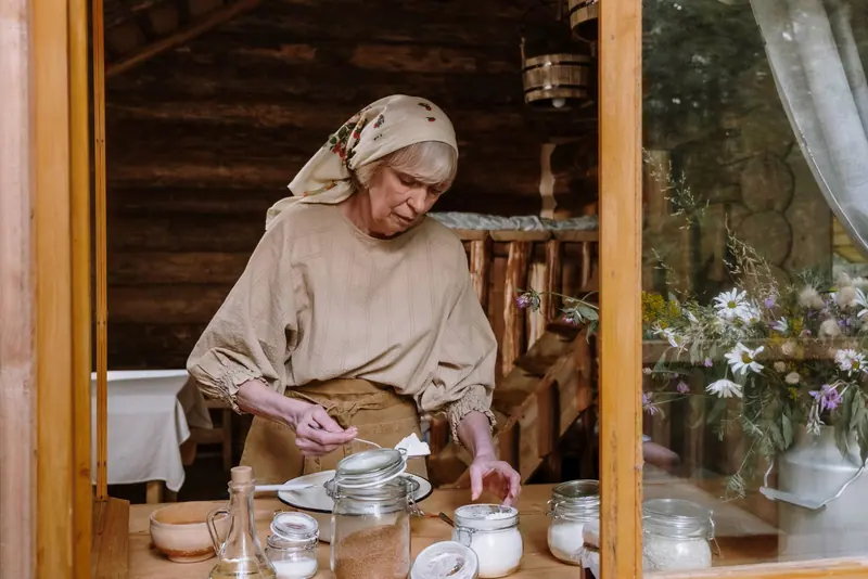 A resident in a headscarf mixing flour at a rustic kitchen table