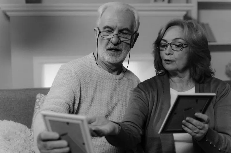 A husband and wife looking at framed family photos
