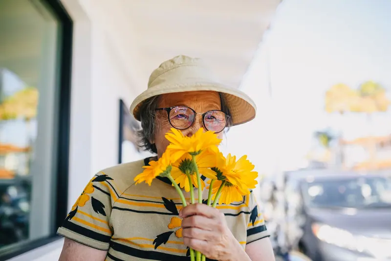 A resident in glasses burying her nose in sunflowers