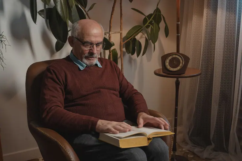 A resident with a book in his leather armchair