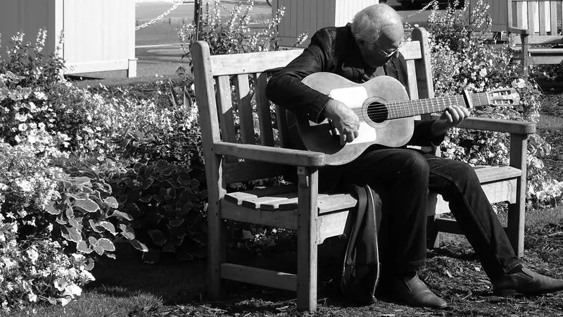 A resident playing guitar on a garden bench