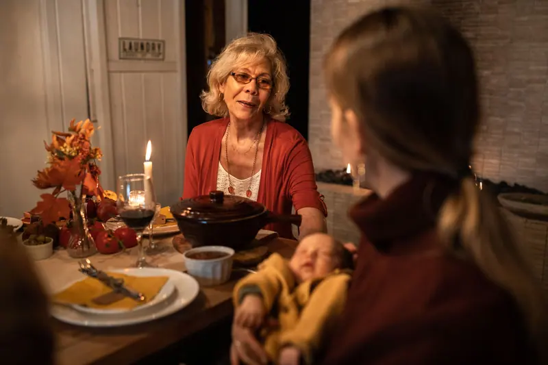 A resident at the harvest table with her granddaughter and the baby