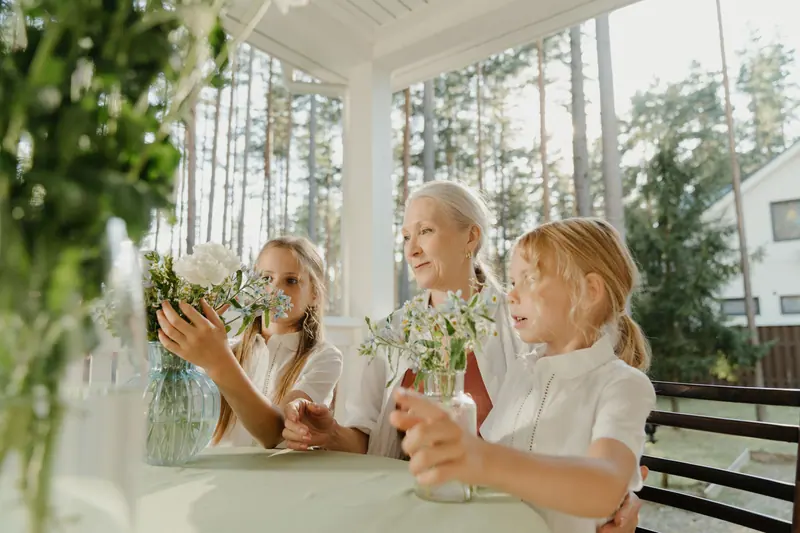 A resident arranging flowers on the porch with her two granddaughters