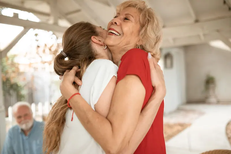 A resident in red laughing as her daughter hugs her