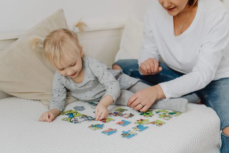 A resident and a toddler working a jigsaw puzzle