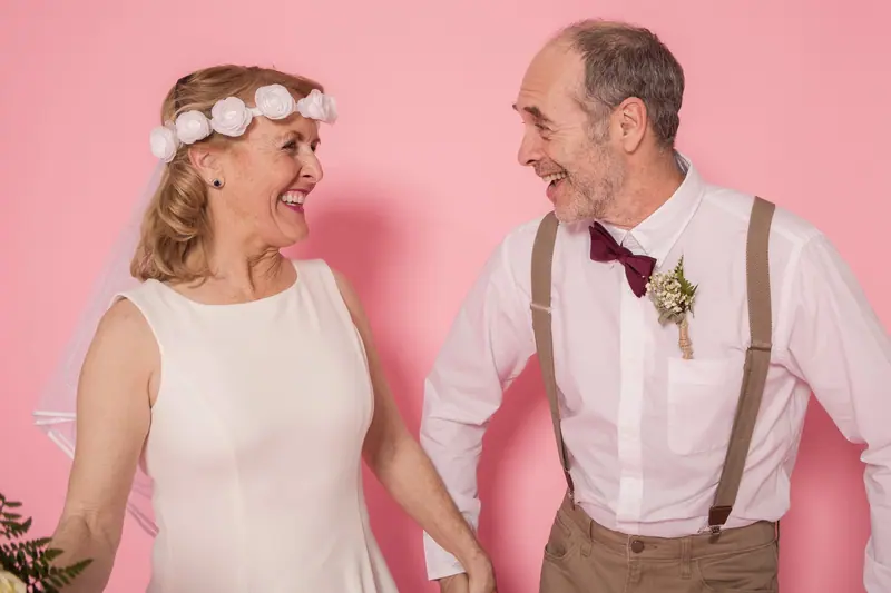 A bride and groom of fifty years laughing at their anniversary party