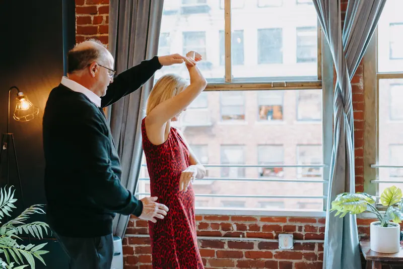 A couple dancing by the tall window